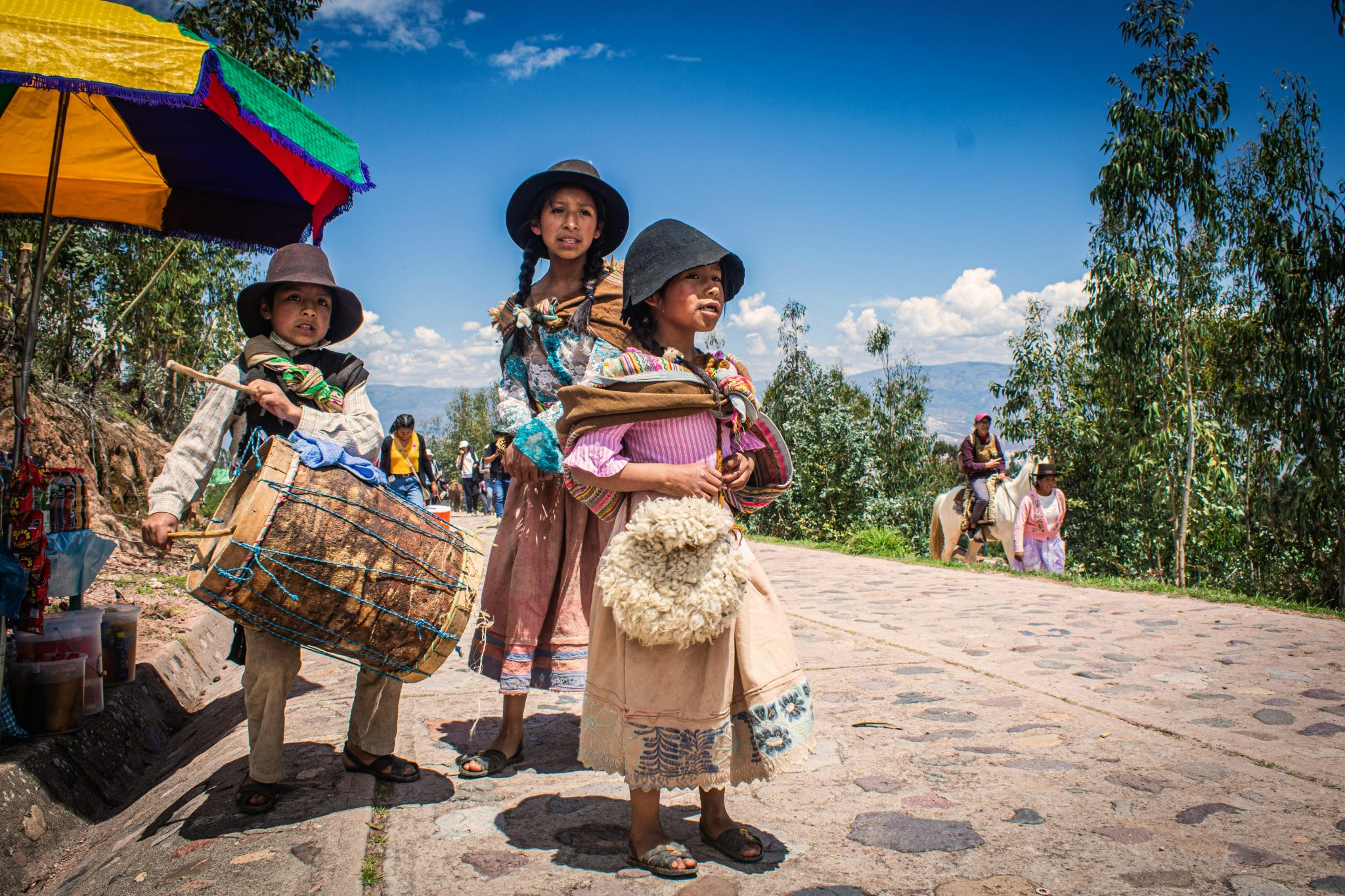 Two children in traditional Peruvian clothing playing drums outdoors in Ayacucho, Peru.